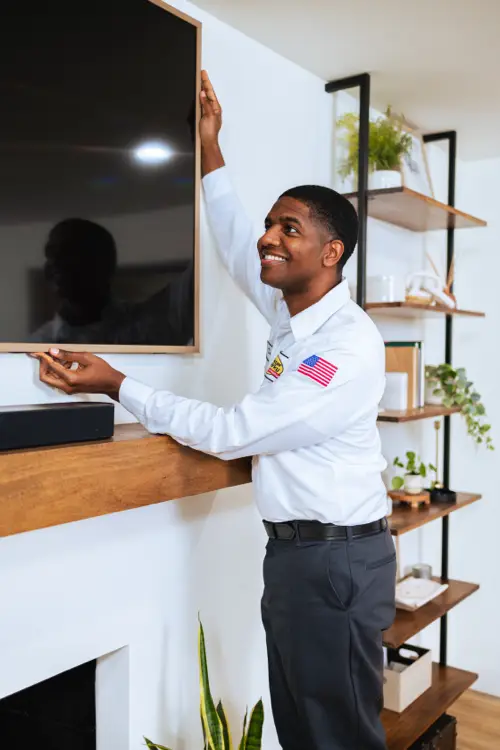 Mister Sparky electrician installing outlet behind wall-mounted TV in Southern Minnesota home